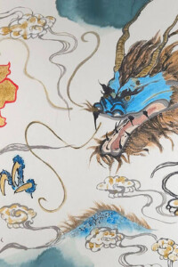 Ein Drache mit einem blauen Kopf kommt aus den Wolken. Ein Teil seines Körpers und seine Klauen sind ebenfalls sichtbar. Er fixiert das chinesische Symbol für Glück.