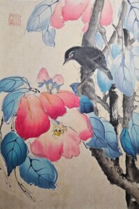 Schwarzer Vogel auf einem Ast zwischen leuchtend roten Blüten und blauen Blättern.
